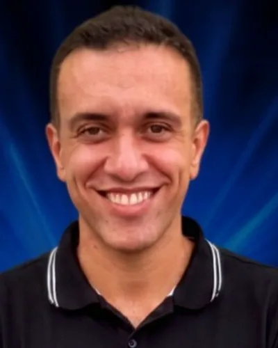 Leandro Ferreira sorrindo, de camisa polo preta e braços cruzados